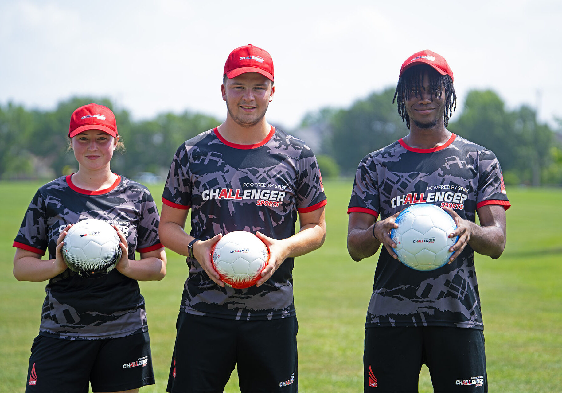 2 male 1 female coach holding soccer ball with both hands standing next to each other smiling posed PHOTO SHOOT